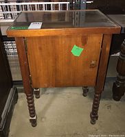 Front view of wooden smokers stand with glass top and closed single door missing knob.