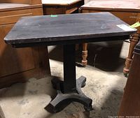 Top view of the small black wooden table showing rectangular surface with signs of wear and scuff marks.