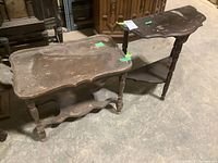 Both tables side by side on concrete floor, showing overall condition, shape and size difference.