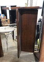 Side view of the wooden church pew showing overall shape and presence of one leg.