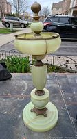 Front angled view of antique ashtray showing tall pedestal, marble base and top bowl with decorative brass finial.