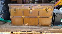 Front exterior of the antique steamer trunk showing metal latches and metal reinforcement strips