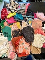 Photo showing an assortment of baby clothes in various colors and patterns laid out on a table.