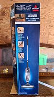 Photo of the vacuum box showing the Bissell Magic Vac PowerBrush branding and features such as motorized brush roll and lightweight design.