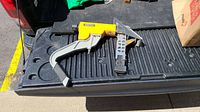 Top view of Bostitch pneumatic flooring nailer showing yellow body and gray handle lying on black truck bed liner.
