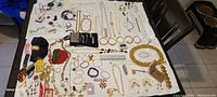 Full assortment of costume jewelry items spread on white cloth showcasing various necklaces, bracelets, bangles, earrings, including Michael Kors and Kate Spade bracelets.