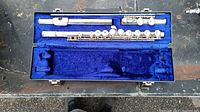 Disassembled Emerson flute in sections inside blue velvet lined interior case.
