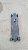Top view of Meepo electric skateboard deck with brand logo and mounted wheels, remote control placed on top of deck.