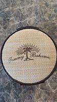 Top view of round leatherette watch case with Tommy Bahama logo on fabric top