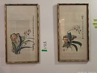Two framed Asian watercolor paintings featuring botanical themes hung side by side on a wall.