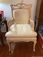 Front view of the chair showing cream upholstered seat cushion and backrest with carved wooden frame.