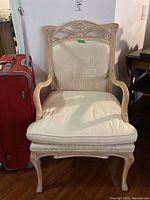 Front view showing wooden carved frame and cream upholstered cushioned seat and backrest