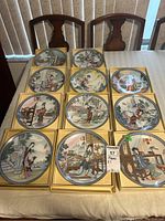 11 collector plates arranged in original gold boxes on a table