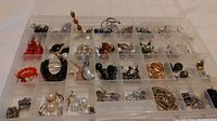 Photo showing all earrings organized in a compartmentalized plastic organizer showing multiple pairs and singles in varied styles and colors.