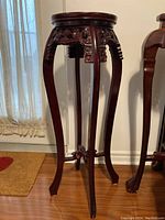 Full view of the ornate wooden plant stand showing its shape, color, and details