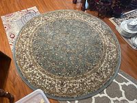 Full view of circular Tabriz rug showing blue center and cream border with floral designs.