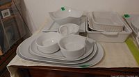 Set of stacked white ceramic serving platters, bowls, divided dish, and plates in various sizes