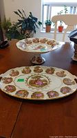 Both pedestal cake plate and serving platter on a table with plants in the background
