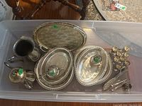 Top-down view of storage bin containing silver plated trays, pitcher, burner, liquor glasses, and cutlery.