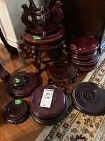 Wide shot showing a variety of wooden stands in various sizes and styles, some with carved legs and others flat. Visible scratches on surfaces.