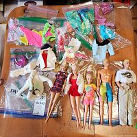 All five dolls with assorted Barbie clothing spread out on a table