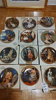 Photo shows 12 Knowles collector plates from the Norman Rockwell Rediscovered Women series displayed in their original boxes on a wooden floor.