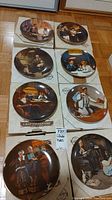 Eight Knowles collector plates arranged on floor, all from Norman Rockwell Light Campaign Series.