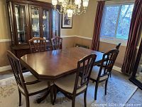 Dining table set with six chairs around the wood octagonal table.