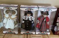 Three porcelain dolls in original Victorian Collection boxes in a row showing front view.