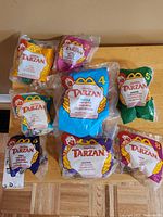 Full set of 8 McDonald's Tarzan toys from 1990 in unopened packaging displayed on table.