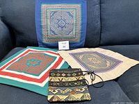 Photo showing 2 pillow covers (one beige, one green), 1 smaller square wall hanging, and 1 small ethnic fabric purse in multicolor geometric ethnic patterns.