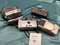All four cameras on green fabric with MaxSold lot card