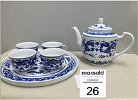 Front view of the dragon-themed tea set showing teapot and four matching cups on a round plate.