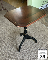 Side angle photo showing the full Hitchcock style side table with decorative inlay around tabletop edges and black pedestal base with gold accent.