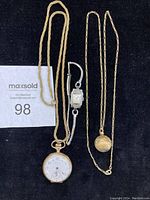 Three ladies' watches including two pendant watches on gold-tone chains and one wristwatch with silver-tone expandable bracelet.