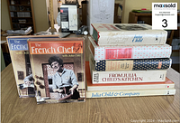 Front view of two DVD box sets and a stack of five cookbooks