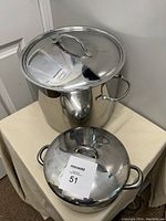 Two stainless steel pots with lids shown stacked on a table, larger 16-quart stockpot on top, smaller 2-quart pot beneath.
