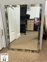 Full view of the rectangular wall mirror showing the entire mirrored and gold decorated trim.