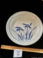 Top view of large round ceramic platter showing hand-painted blue iris flowers and leaves with a measuring ruler indicating approximately 15 inches diameter.