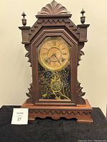 Full view of antique Victorian mantel clock showing carved wooden case and decorative glass front with floral design