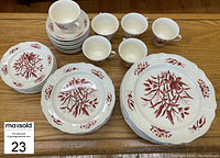 Photo showing the full set of plates, cups, and saucers arranged on a table with number 23 MaxSold tag.