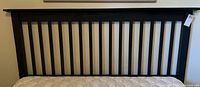 Front view of black wooden queen size headboard showing vertical slats and condition with scratches