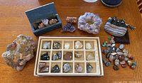 Overview of entire collection laid out on table including a large porous rock, case with labeled specimens, crystal formations, blue box, and pouches of stones.