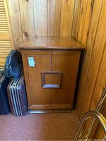 Front view of the wood cabinet showing two doors with recessed rectangular handles and smooth wood finish.