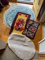 Overview photo showing all five carpets including large blue round, floral rectangular, multicolor patchwork rectangular, and two oval white and beige rugs.