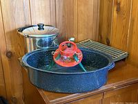 Photo showing the Christmas tree stand on top of the black speckled roaster pan, with the stainless steel pot and oven tray behind them.