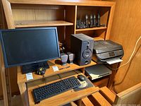 Photo showing Dell monitor, keyboard, mouse, Harman Kardon speakers, HP printer, Panasonic cordless phone set on wooden shelving unit.