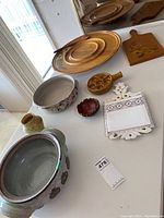 Overview of all kitchen serveware items including wooden Lazy Susan, pottery bowls, escargot server, trivet, and cutting board.