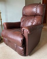 Side angled view showing the overall shape, padded armrests, and leather condition with some fading.