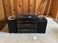 Front view of stacked Sony audio components with turntable on top, flanked by two Celestion speakers and two remote controls on right speaker.